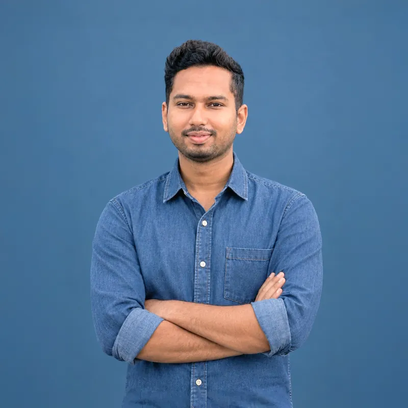 Professional portrait of Sefat Khan in a blue denim shirt with arms crossed, smiling