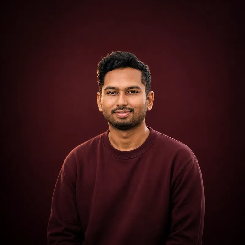 Portrait of Sefat Khan, technology and digital creator, in a maroon sweater against a dark red background