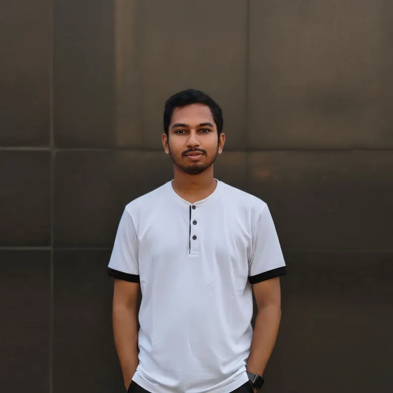 Sefat Khan standing in a white henley shirt against a dark wall